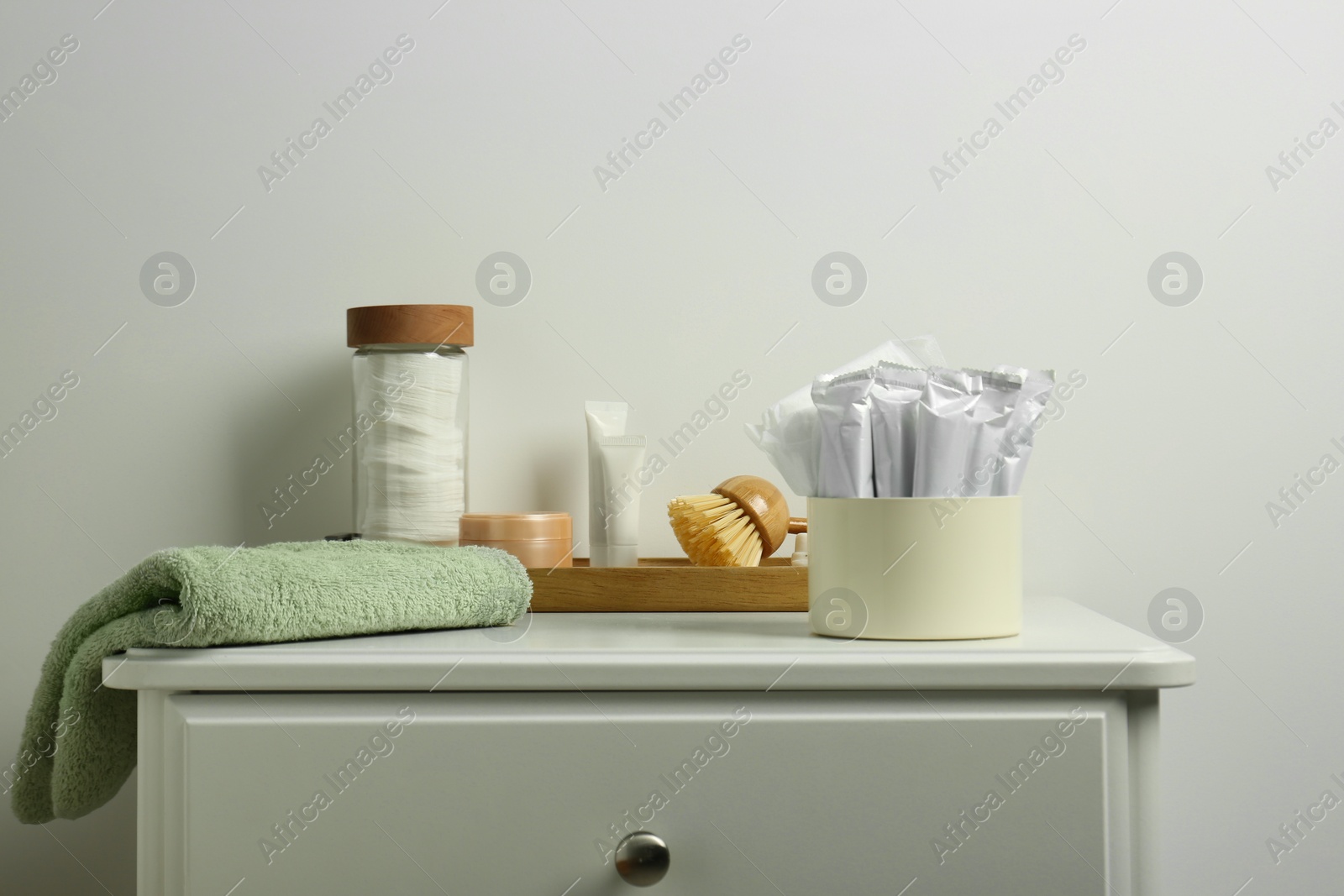 Photo of Different feminine and personal care products on white nightstand near white wall