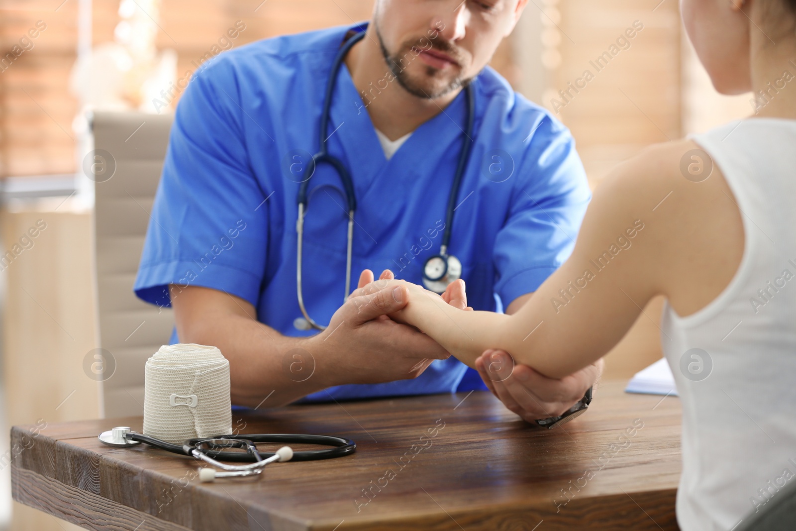 Photo of Male orthopedist examining patient with injured arm in clinic, closeup