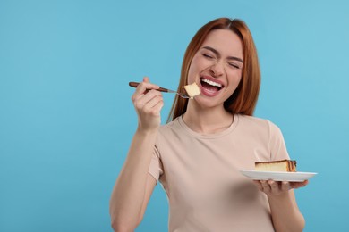 Photo of Young woman eating piece of tasty cake on light blue background, space for text