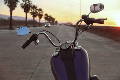 Photo of Modern black motorcycle on road at sunset
