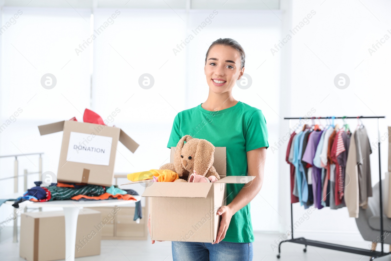 Photo of Young woman holding box with donations indoors