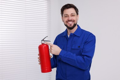 Photo of Man in uniform with fire extinguisher indoors