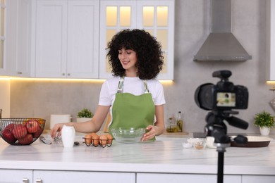 Photo of Smiling food blogger cooking while recording video in kitchen