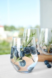 Photo of Refreshing blueberry cocktail with rosemary on table