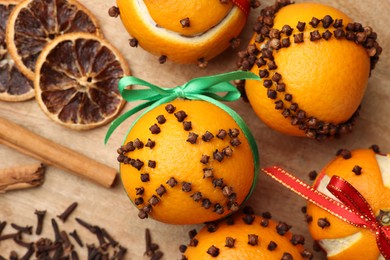 Photo of Pomander balls made of tangerines with cloves on wooden table, flat lay