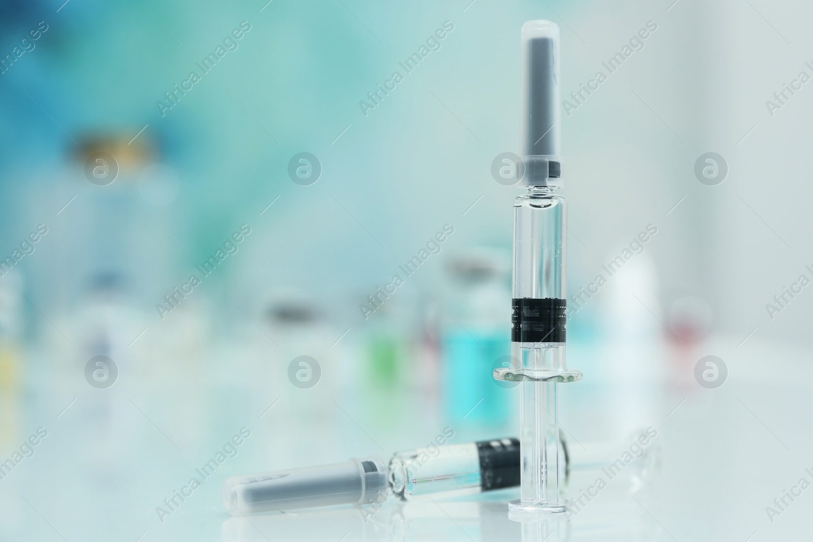 Photo of Syringes with COVID-19 vaccine on white table, space for text
