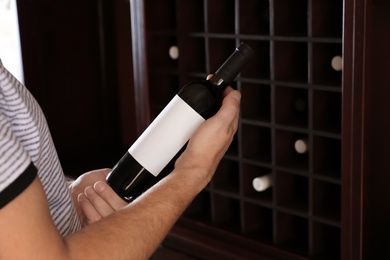 Photo of Man with bottle of expensive wine indoors, closeup
