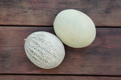 Whole ripe cantaloupe melons on wooden table, flat lay