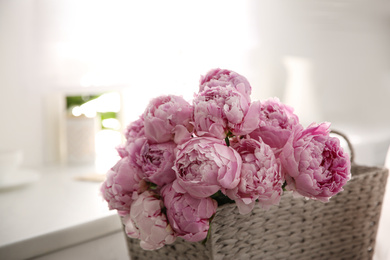 Photo of Basket with beautiful pink peonies in kitchen