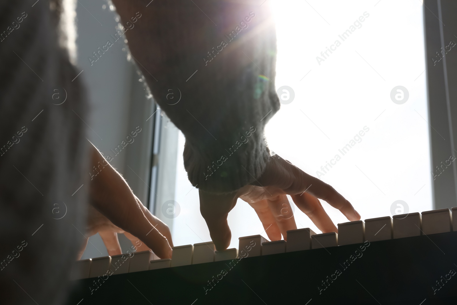 Photo of Young woman playing piano near window at home, closeup