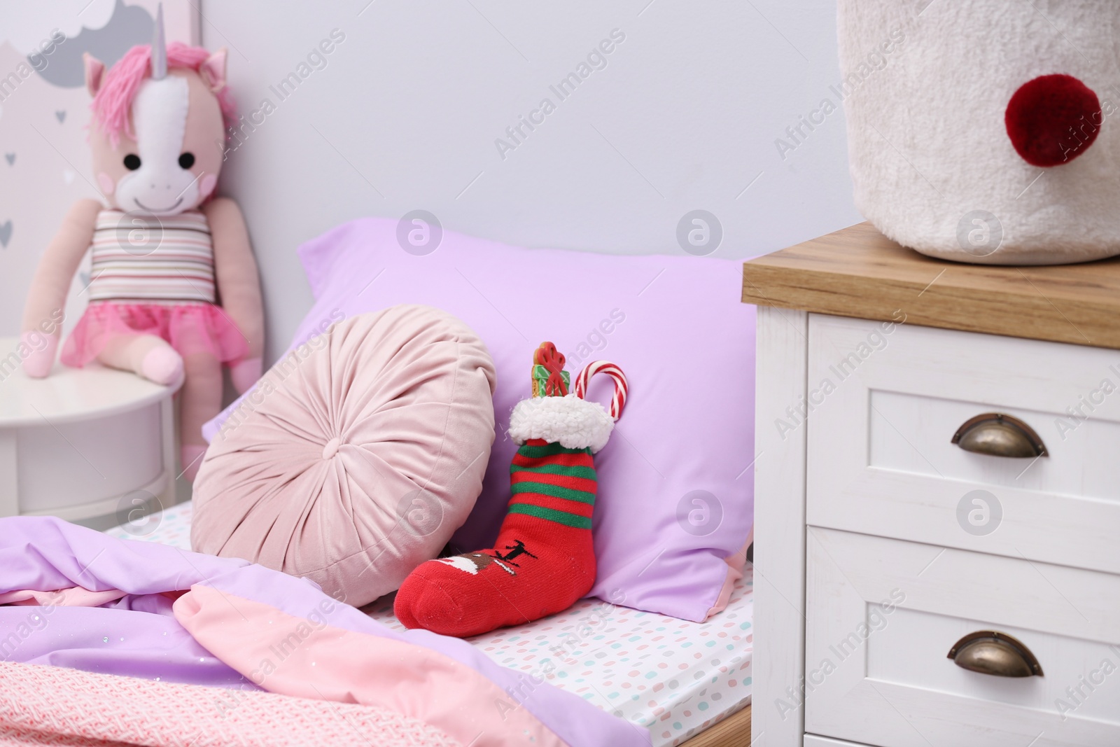 Photo of Stocking with presents on bed in children's room. Saint Nicholas Day tradition