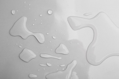 Photo of Drops of spilled water on grey background, top view