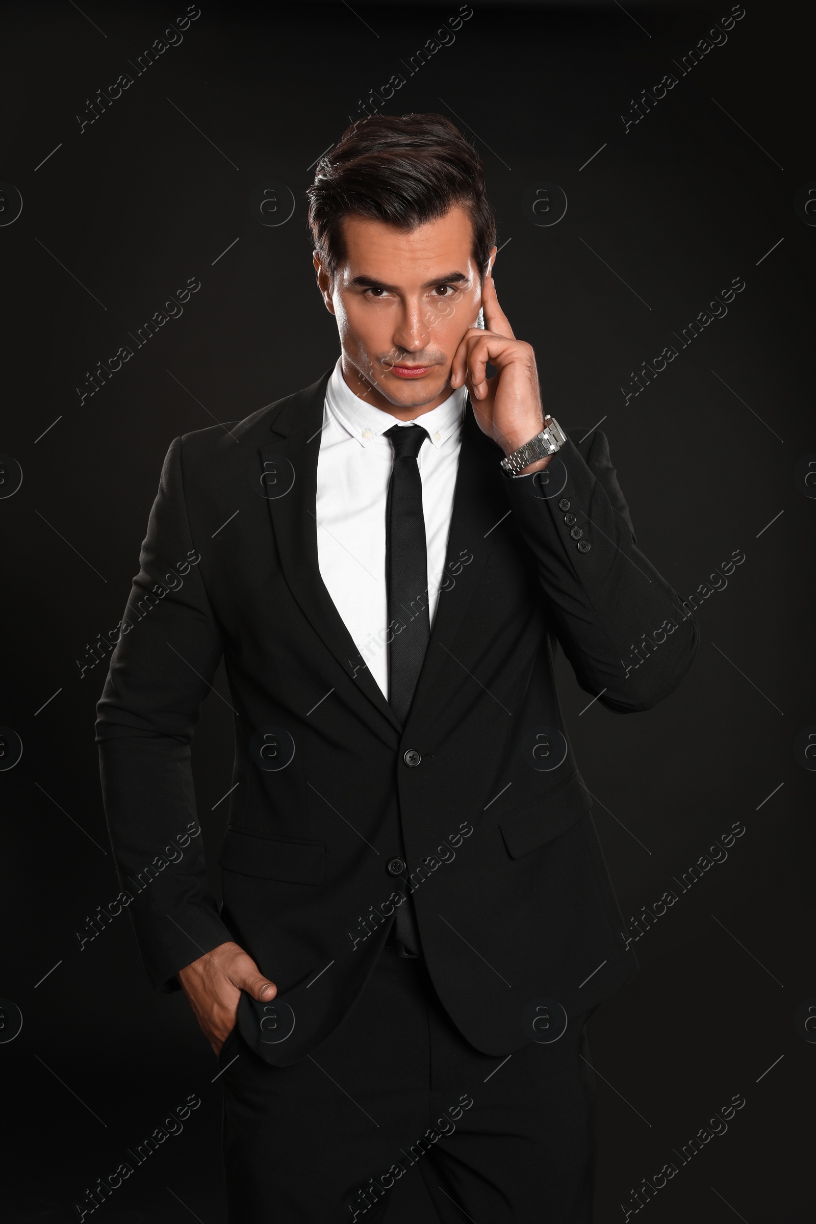 Photo of Male security guard in uniform using radio earpiece on dark background