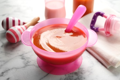 Bowl of healthy baby food on white marble table, closeup