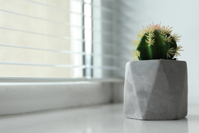 Beautiful artificial plant in flower pot on window sill. Space for text