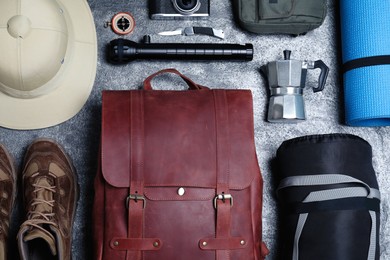 Photo of Flat lay composition with leather backpack and camping equipment for tourism on grey background
