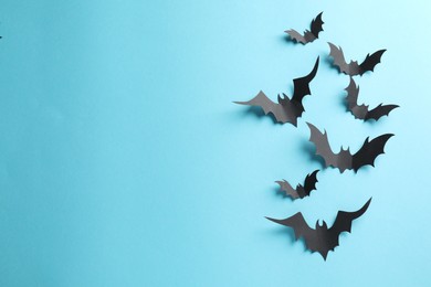 Photo of Flat lay composition paper bats on light blue background, space for text. Halloween decor