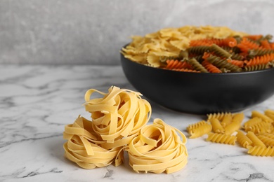 Different types of pasta on white marble table