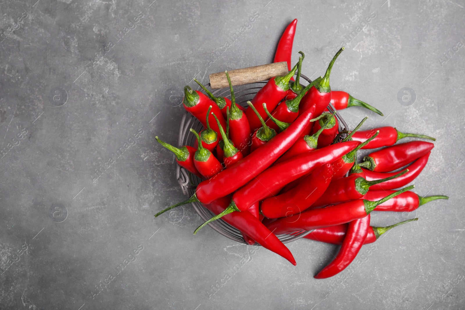 Photo of Basket with ripe chili peppers on grey background, top view