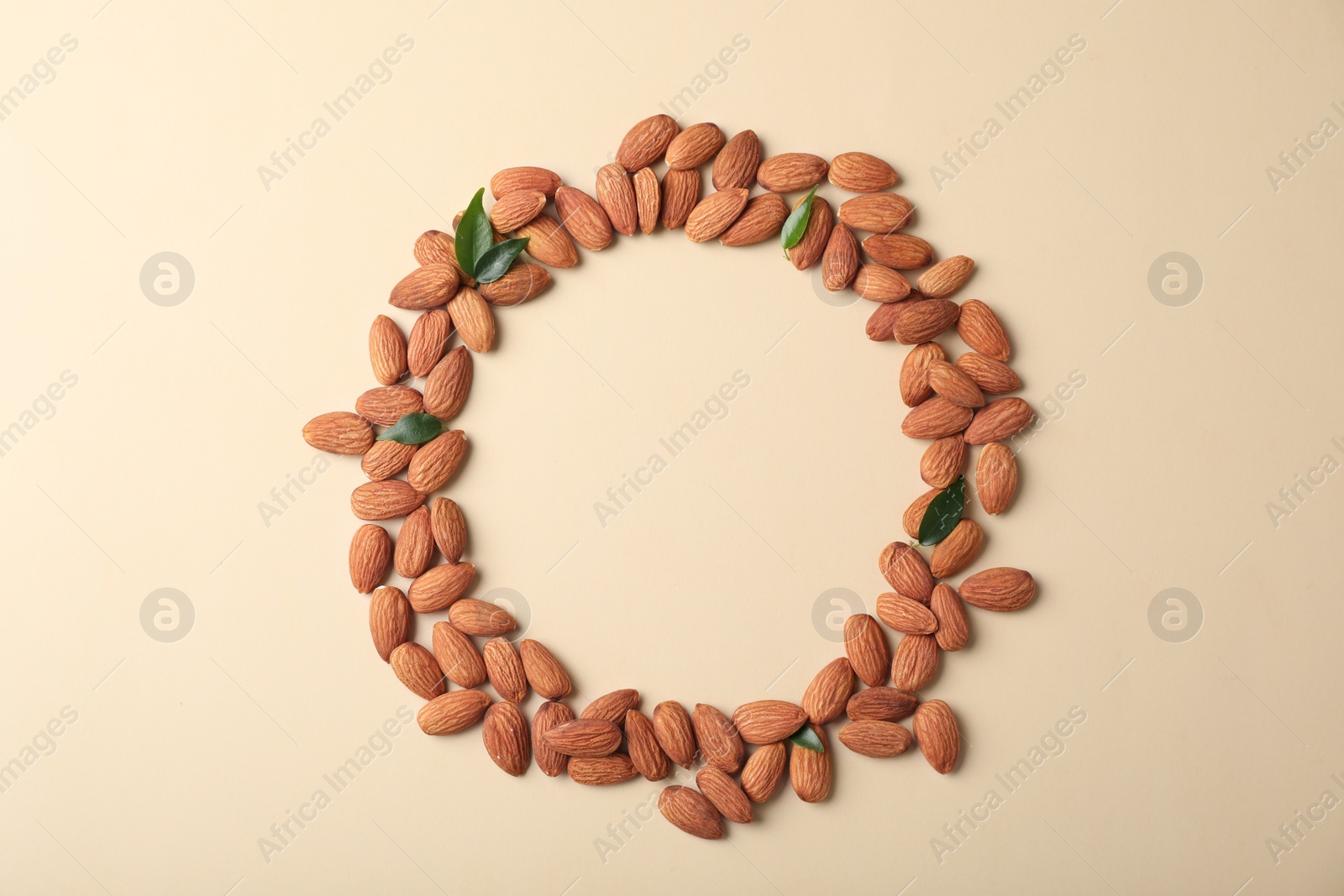 Photo of Frame made of organic almond nuts on color background, top view. Space for text