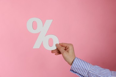 Photo of Woman holding percent sign on pink background, closeup