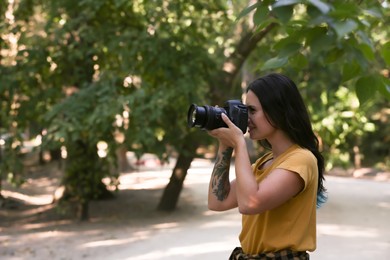 Beautiful woman with camera spending time in nature reserve