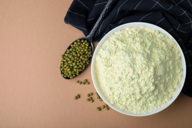 Photo of Bowl of flour, spoon and mung beans on beige background, flat lay. Space for text