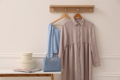 Wooden shelf with fashionable clothes on white wall in room. Interior element