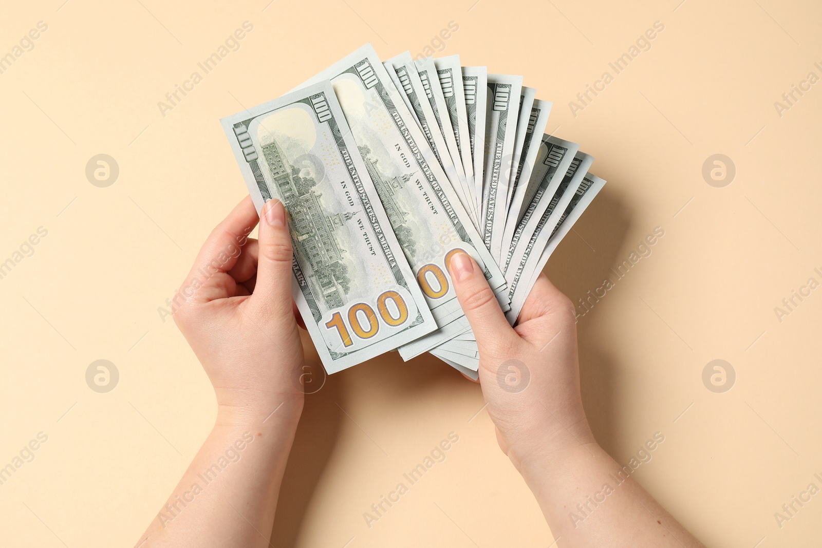 Photo of Money exchange. Woman holding dollar banknotes on beige background, top view