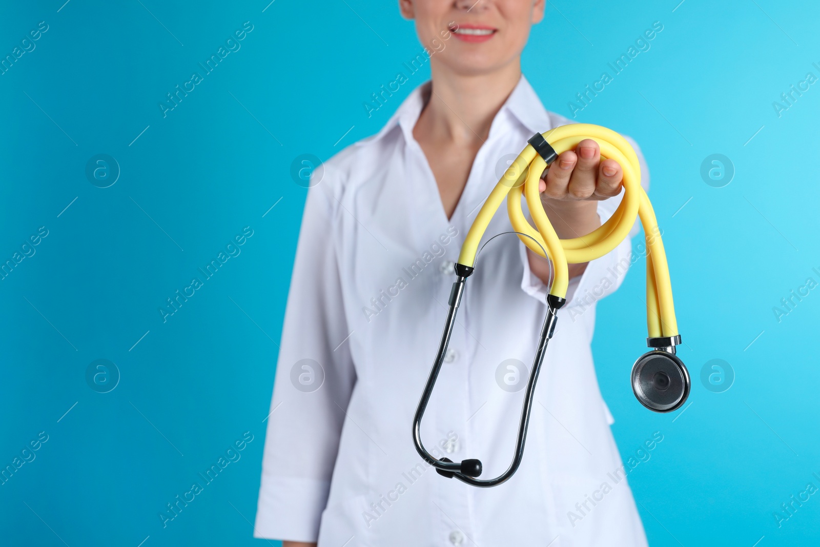 Photo of Female doctor holding stethoscope on color background, closeup view with space for text. Medical object