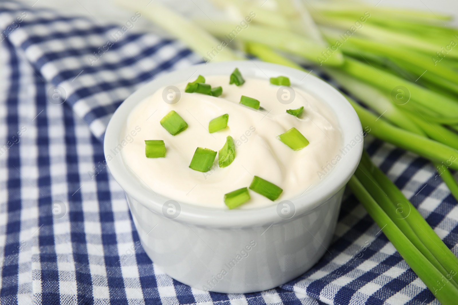 Photo of Fresh sour cream with onion on fabric, closeup