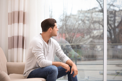 Handsome man resting on couch near window at home