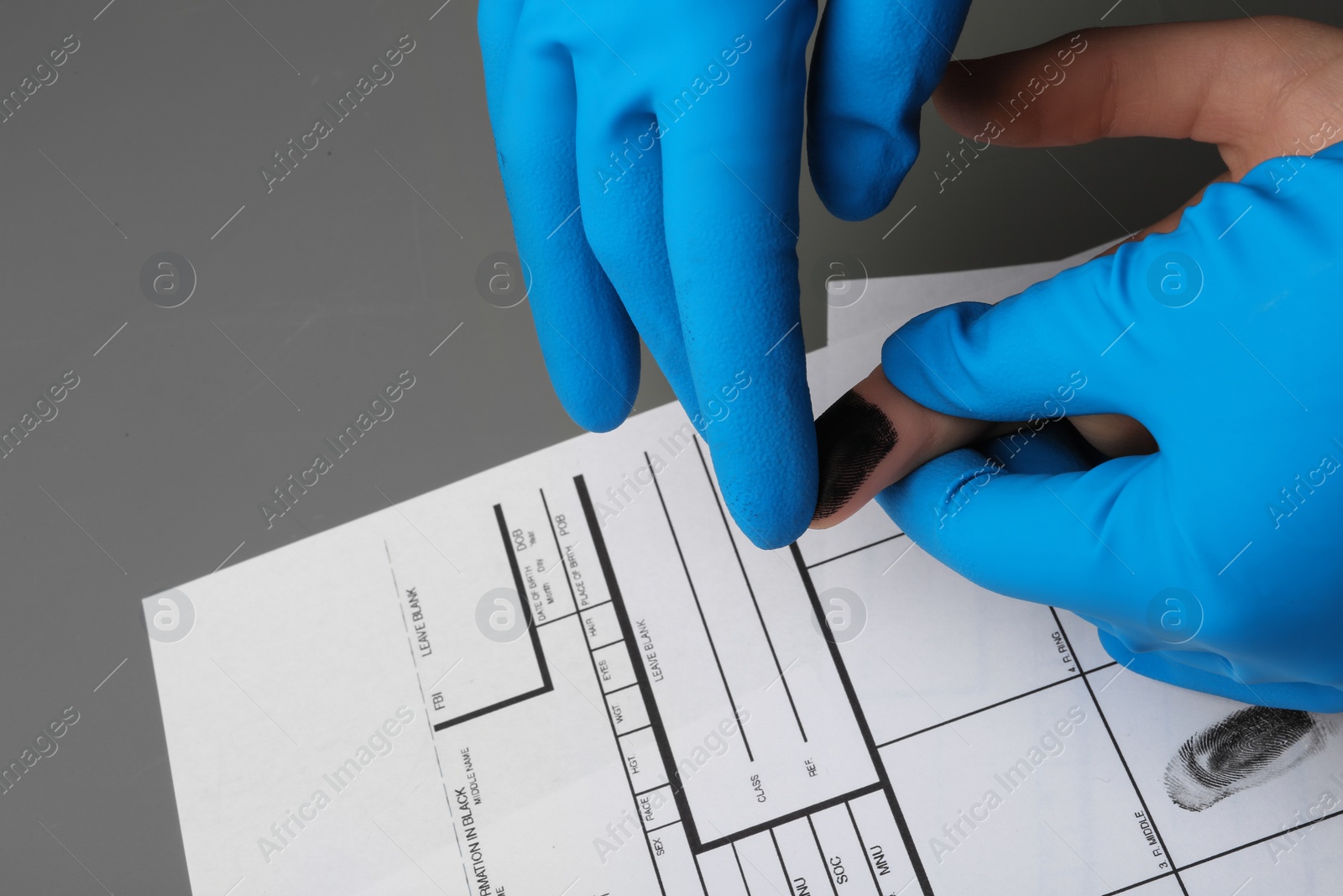 Photo of Investigator taking fingerprints of suspect at table, closeup. Criminal expertise