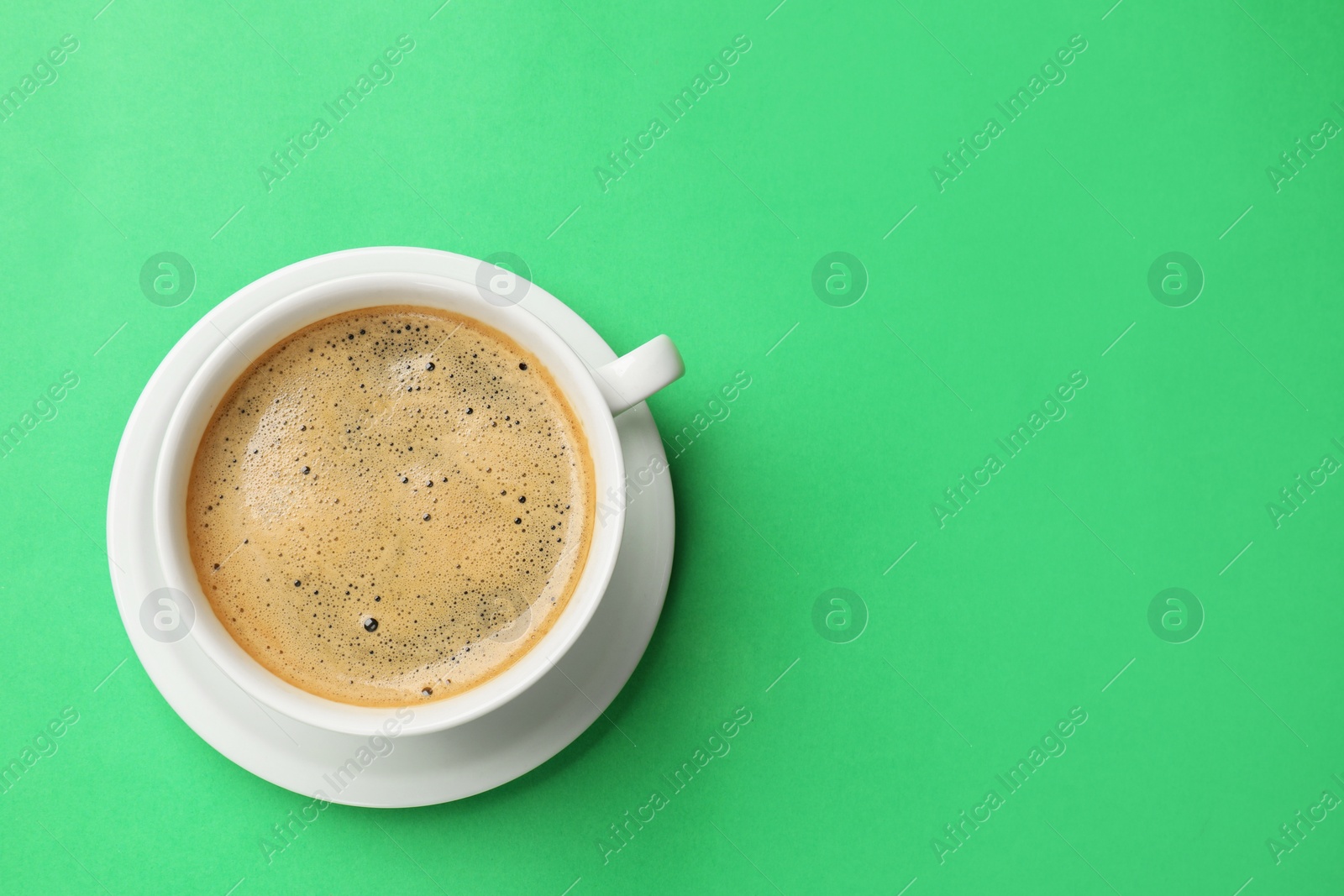 Photo of Aromatic coffee in cup on green background, top view. Space for text