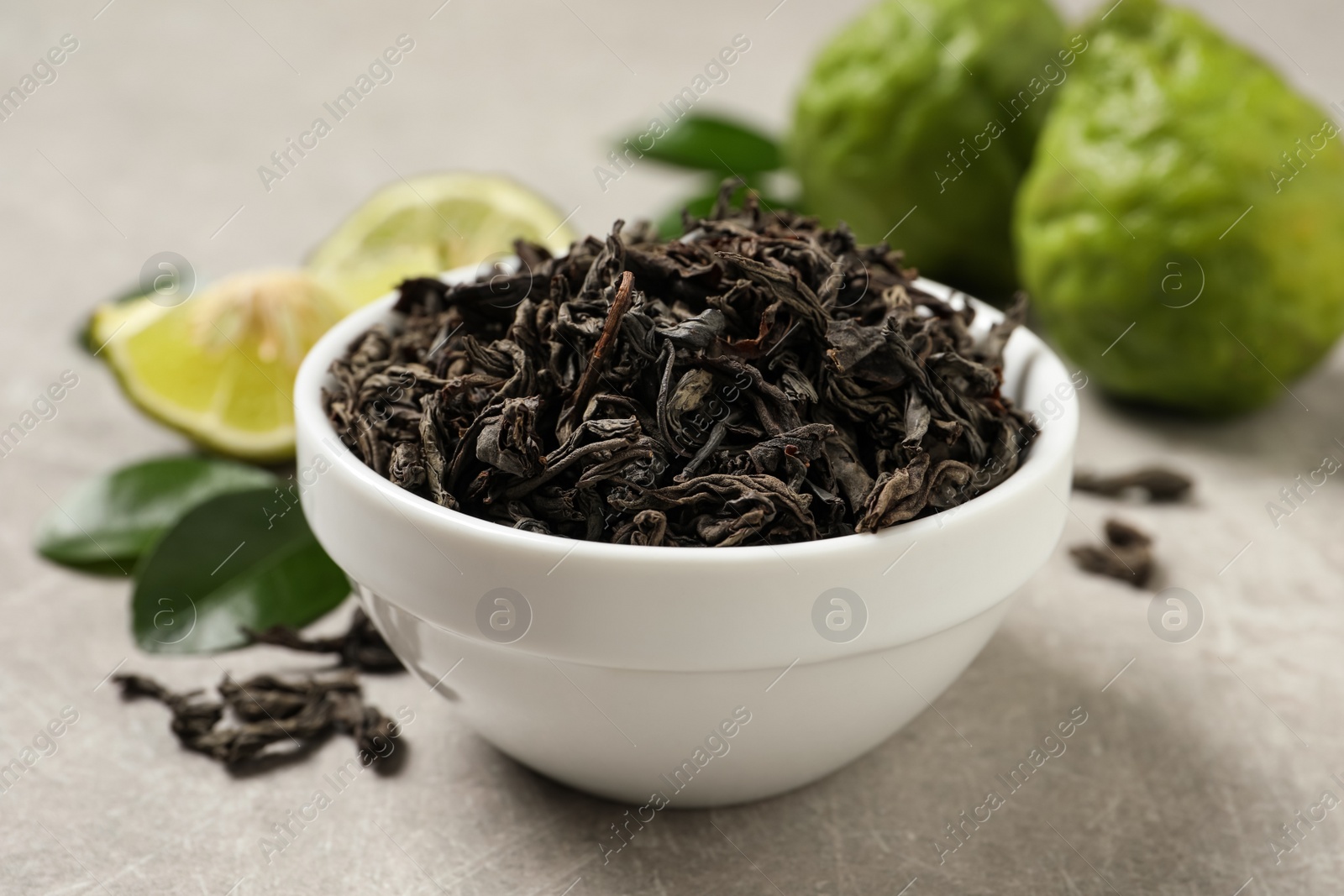 Photo of Dry bergamot tea leaves and fresh fruits on light grey table, closeup