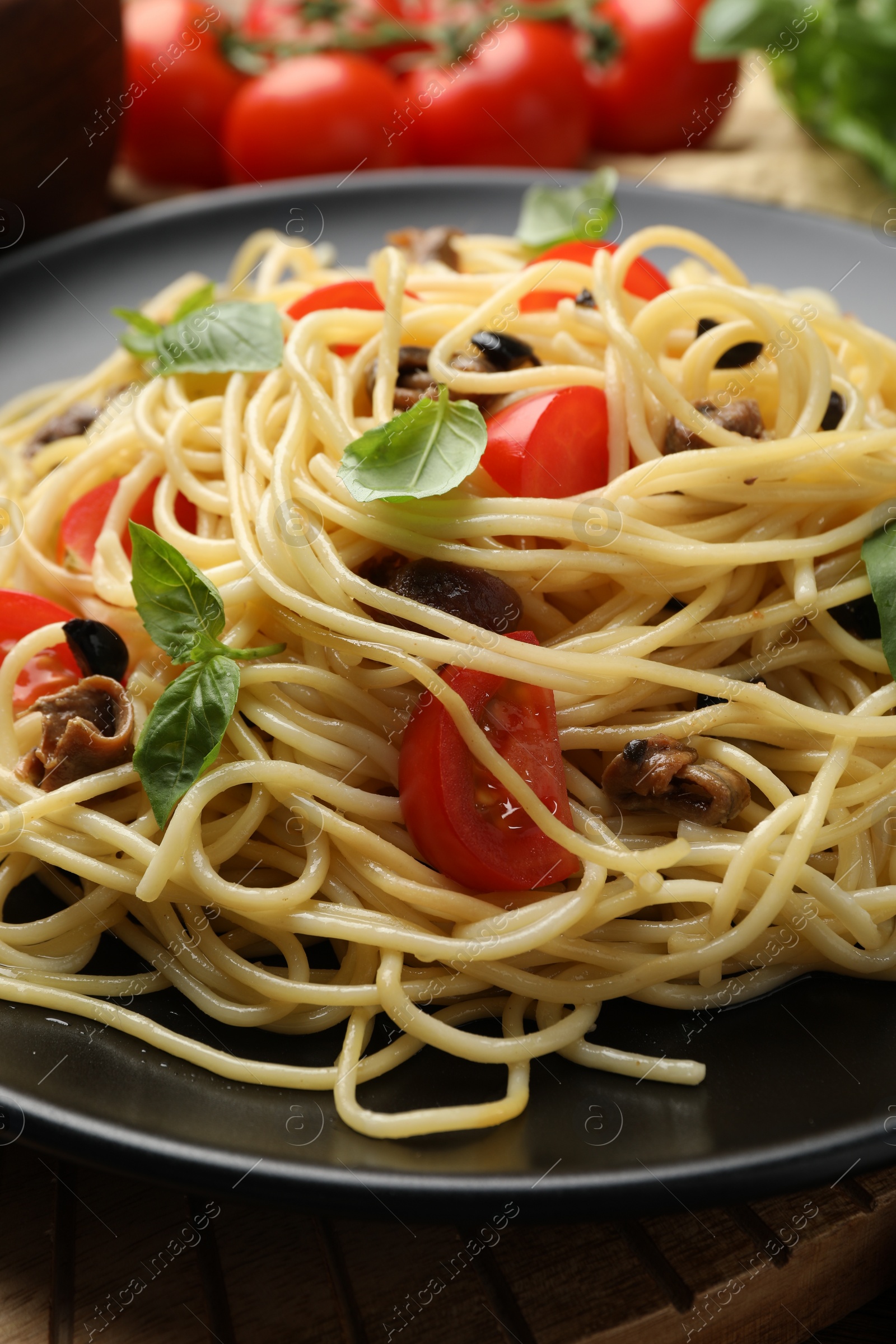 Photo of Delicious pasta with anchovies, tomatoes and olives on table, closeup