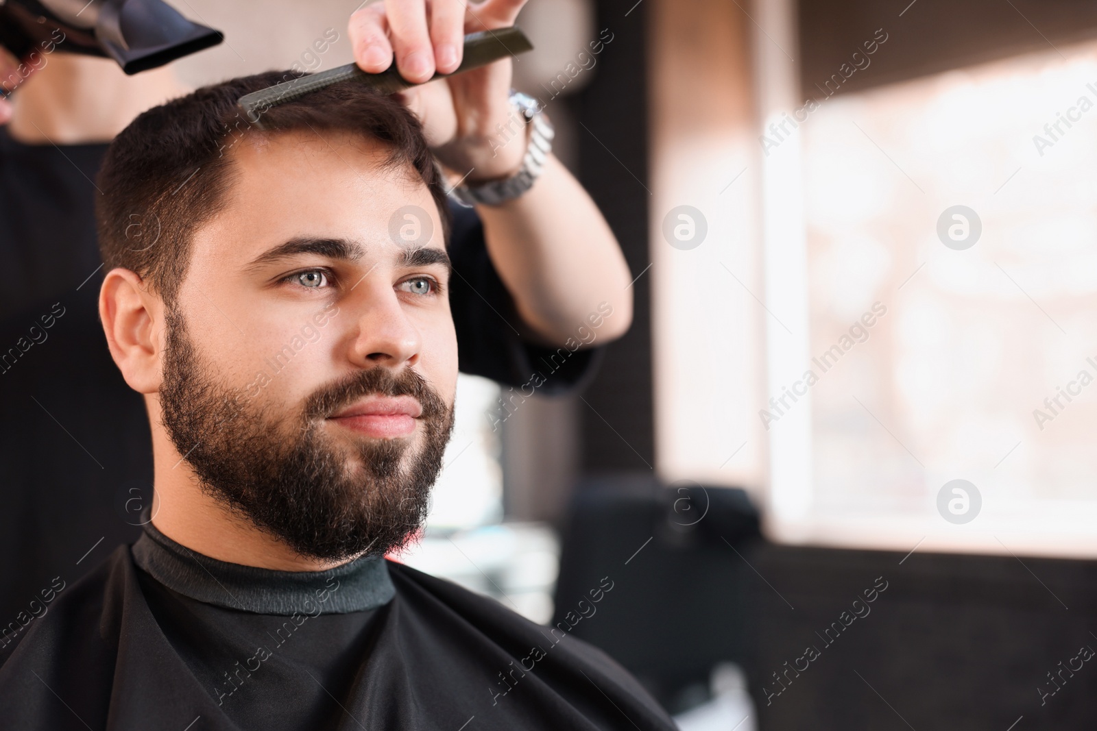 Photo of Professional hairdresser working with client in barbershop