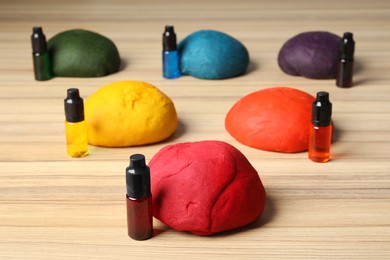 Photo of Colorful dough and bottles with food colorings on wooden table