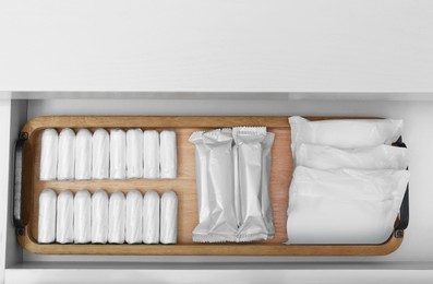 Photo of Storage of different feminine products in white drawer, top view