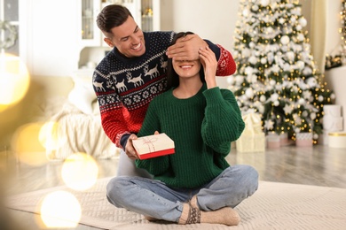 Man presenting Christmas gift to his girlfriend at home