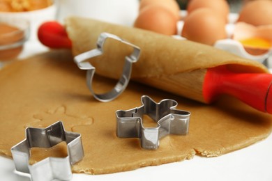 Photo of Cookie cutters, dough and rolling pin on white table, closeup. Christmas biscuits