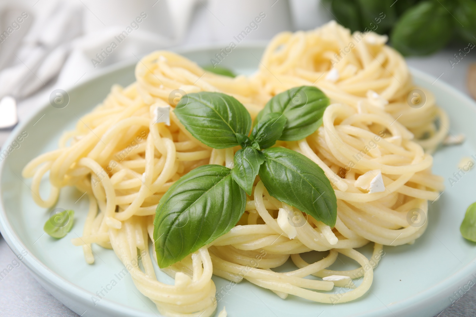 Photo of Delicious pasta with brie cheese and basil leaves on table, closeup