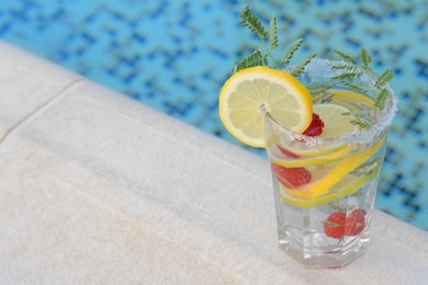 Delicious refreshing lemonade with raspberries near pool, space for text