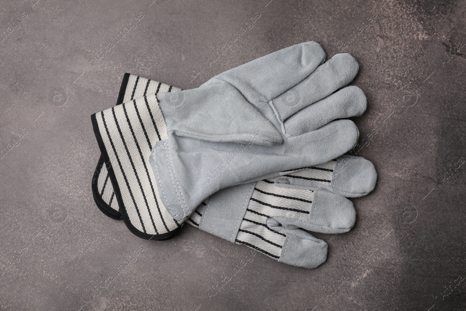 Photo of Pair of color gardening gloves on brown textured table, top view