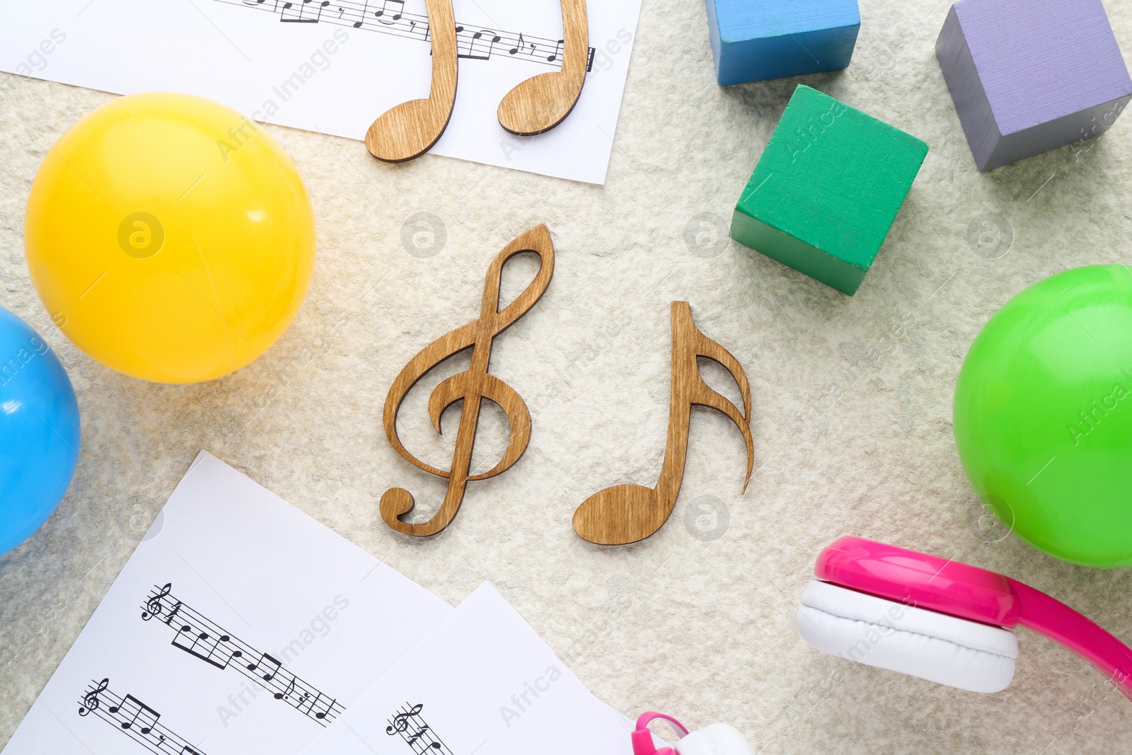 Photo of Wooden notes, music sheets and toys on beige textured background, flat lay. Baby song concept