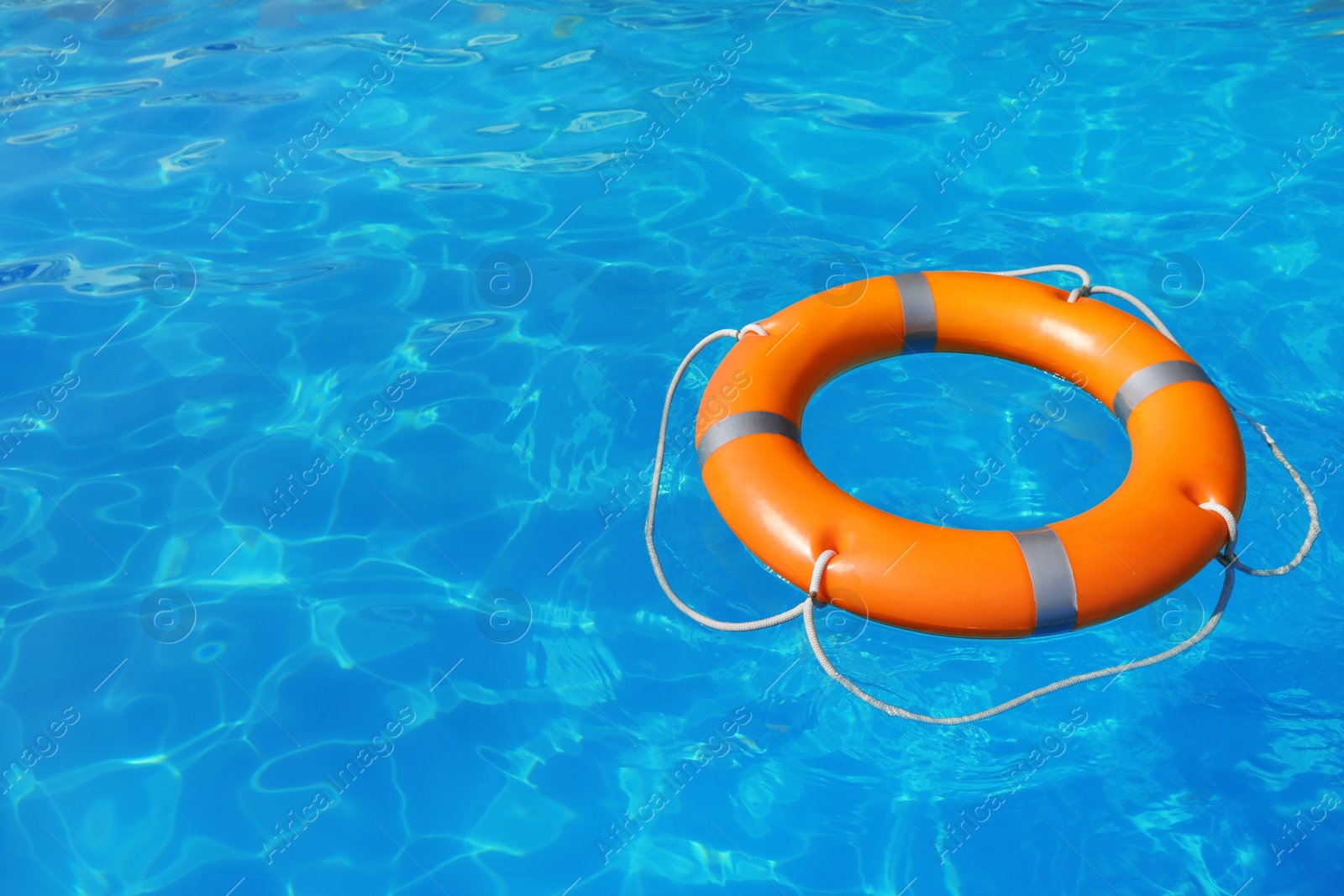 Photo of Lifebuoy floating in swimming pool on sunny day. Space for text