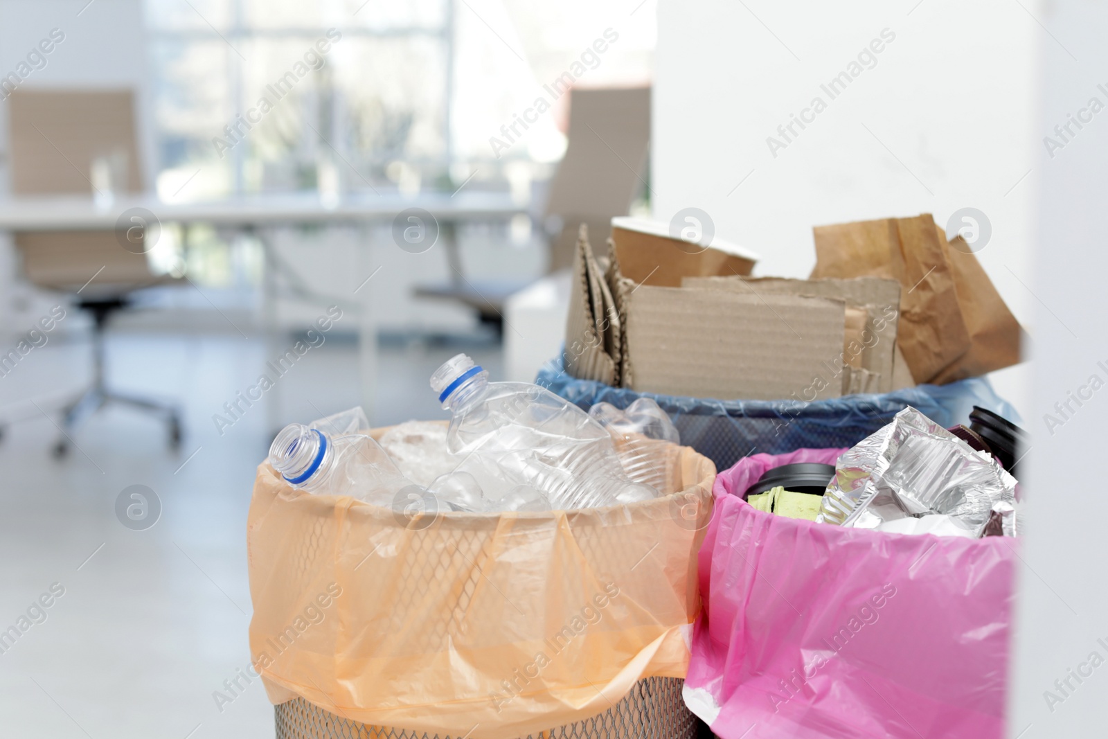 Photo of Full trash cans in modern office, space for text. Waste recycling