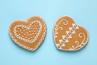 Photo of Gingerbread hearts decorated with icing on light blue background, flat lay