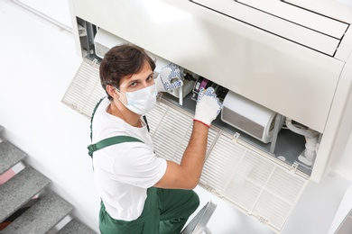 Photo of Young male technician repairing air conditioner indoors