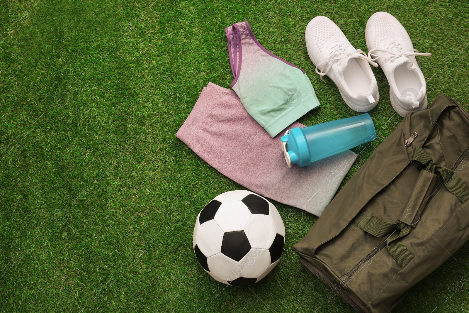 Photo of Gym bag and sports equipment on green grass, flat lay. Space for text